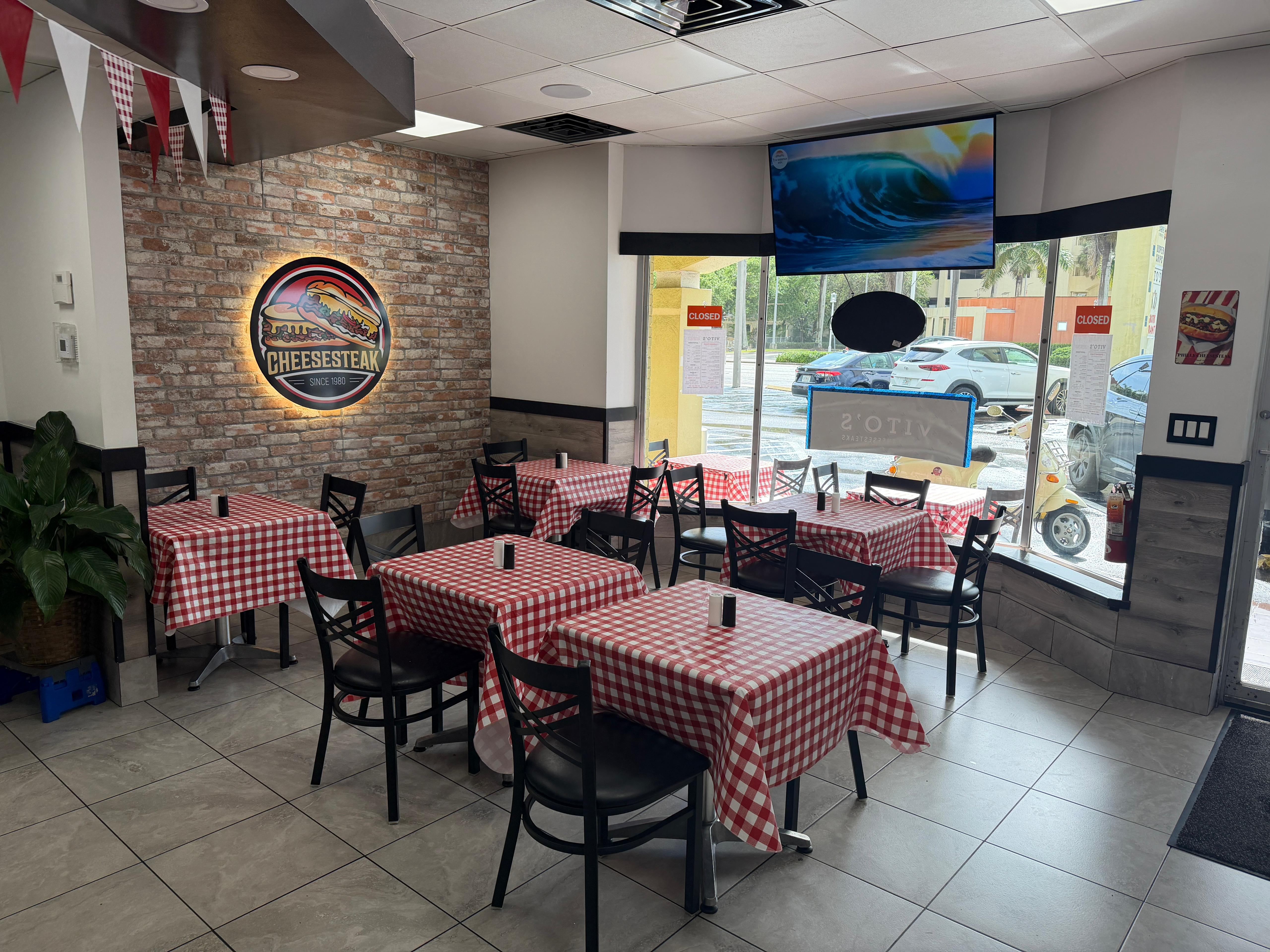 Vito's Famous Cheesesteaks illuminated logo on brick wall